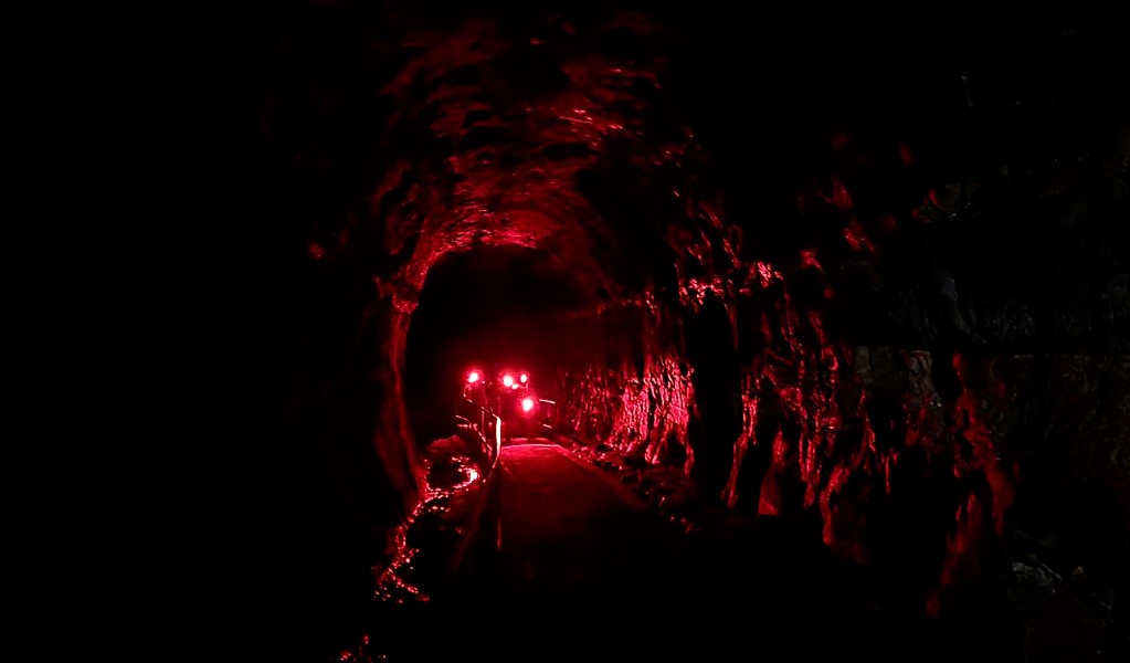 A group of people with red light torches walking through the dark at Glow Worm Tunnel in Wollemi National Park. Photo: Blake North &copy; Red Lantern Tours