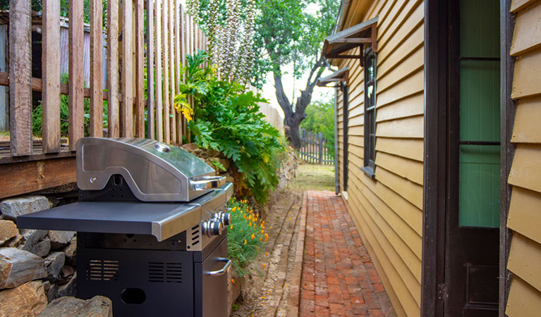 A pathway around the side of Sydney Hotel Cottage with barbecue and trees in the background. Photo: Steve Garland &copy; DPIE