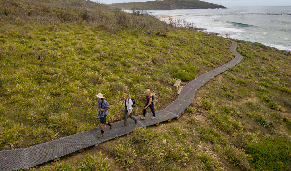 3 bushwalkers on raised path on the Murramarang South Coast Walk. Credit: John Spencer &copy; DPE